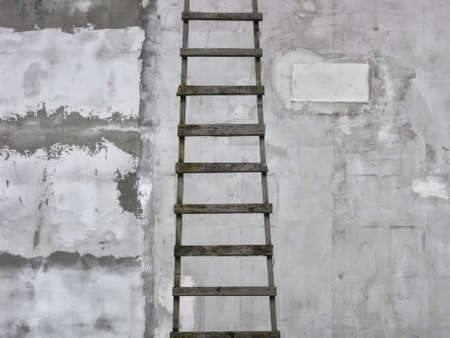 Wooden ladder on the background of gray textured plaster wall in minimalistic style.の写真素材