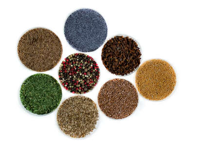Herbs and seasonings - dried coriander, peppercorn, flax seeds, mustard, clove, cumin, parsley and poppy seeds in a transparent dish isolated on white background.の写真素材