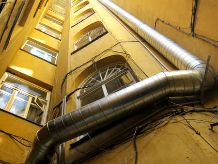 Old building with stainless steel ventilation pipe and electricity wires.の写真素材