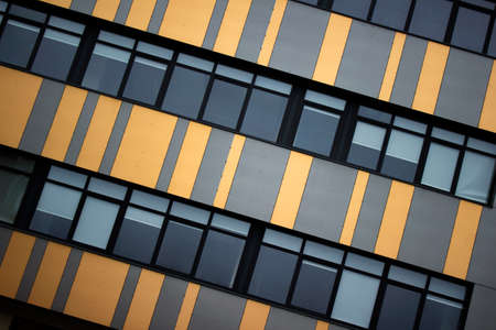Office building's diagonal window pattern in orange, gray, blue and black colors.の写真素材