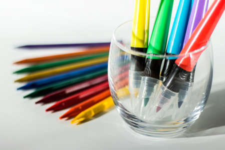 Drawing utensils - colorful crayon pencil and markers in a glass holder on white background.の写真素材