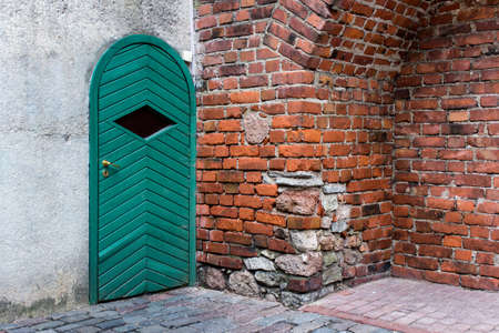 Exterior of vintage building - red brick wall with green wooden door in old city. Ancient times.の写真素材