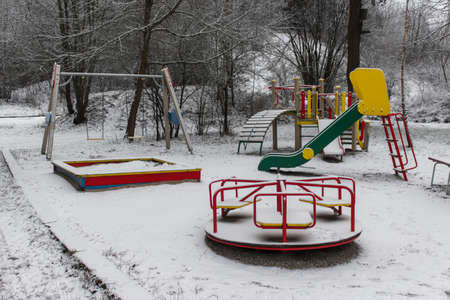 Empty children playground in winter. Snow covered merry go round.