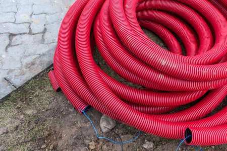 Red plastic pipes for underground electrical wires lying on the ground ready to be installed.の写真素材