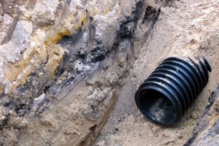 Black plastic pipe under the ground. Water supply system, infrastructure. Reparation works.