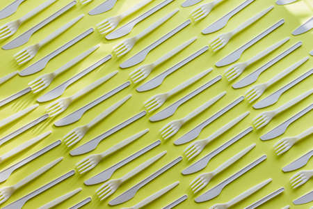Diagonal dense repeating pattern with white forks and knives on yellow background. Kitchen utensils.