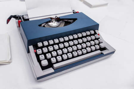 Old fashioned blue typing machine on white backgound. 