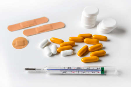 Thermometer, patches for wounds, capsules, tablets for healing fever, cold on white background.の写真素材