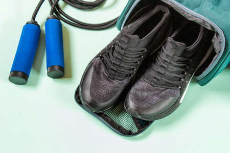 Handles of jump rope with sport shoes in the sport bag on minty green background. Sport equipment for healthy lifestyle.の写真素材