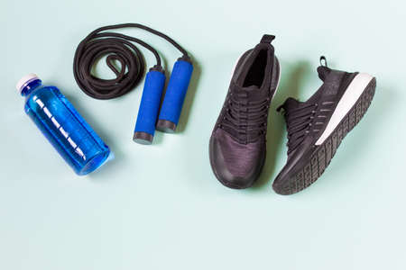 Sport fitness layout with sport shoes, jumping rope and blue bottle with water on minty green background with blank space.の写真素材