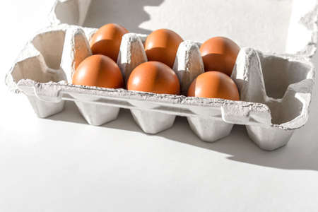 Six brown eggs in carton packaging box on white background.の写真素材
