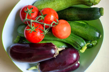 Top view of various vegetables - aubergine, zucchini and tomatoes in a bowl.の写真素材