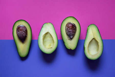 Avocado pieces parts laying on double color background - pink and blue.