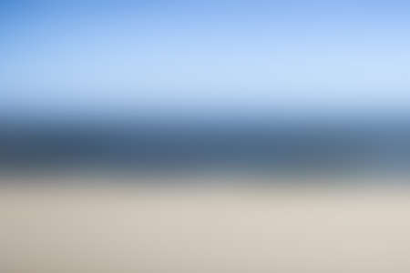 Shore of Baltic sea with empty sandy beach and blue sea with waves. Photo with extreme blur effect. Ocean water gradient. Good for lettering presentations.の写真素材