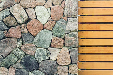 Stone wall made of decorative ancient old looking large stones and wooden fence. Elements of garden design.の写真素材