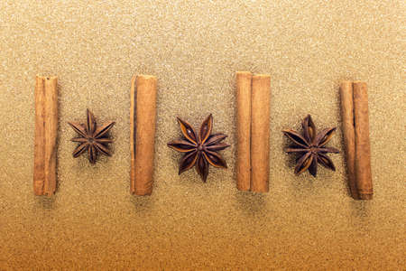 Cinnamon sticks and anise herbs on golden glitter backgound. Decorative Christmas baking aroma smell.の写真素材
