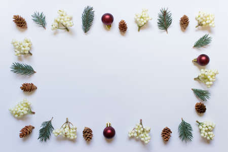 Christmas decorative mock up border made of decorative elements fir branch, wooden cone, red ball arranged in frame border on white backgound.の写真素材