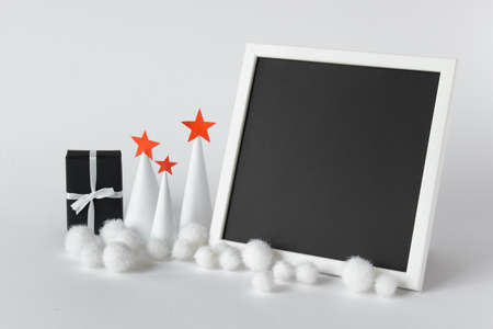 Large picture photo frame template with inserted black blank paper and Christmas paper trees with stars and a present.の写真素材