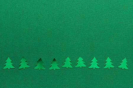 Simple minimalistic winter Christmas background a line row of shiny glossy green Christmas fir trees...