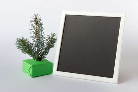 Large picture photo frame template with inserted black blank paper and little Christmas fir tree on...