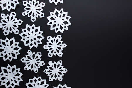 Black and white Christmas winter festive simple background with large white handmade paper snowflakes on black background.の写真素材