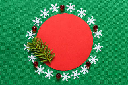 Winter background with snowflakes arranged in a circle along red paper circle on green textured...
