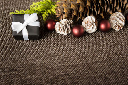 Warm Christmas composition layout with red balls, white wooden pine ccones, little present arranged...