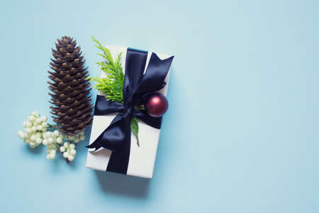 Winter Christmas New Year greeting card composition with a present, red ball, pine cone on blue...