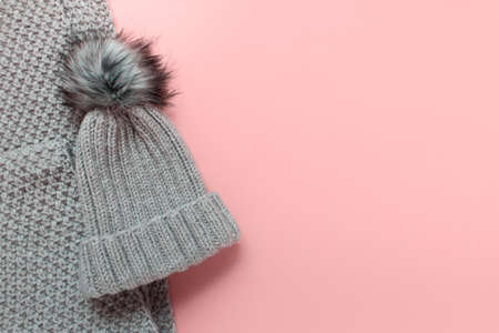 Warm winter wardrobe handmade hat beanie with pompom and knitted large scarf on pink background. Photo with copy blank space.の写真素材