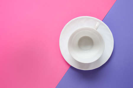 Single one porcelain white empty cup on a dish on pink purple double background. Photo with copy blank space.の写真素材