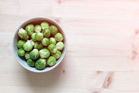 Green brussel cabbages in a bowl on wooden background. Photo with copy blank space.の写真素材