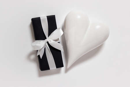 Valentine's, Mother's, Father's day greeting card white porcelain heart and present with white satin ribbon on white background.の写真素材