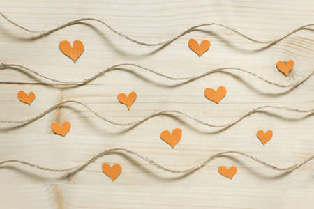 Abstract Valentine day pattern with wavy rough rope packthread on wooden background with small yellow hearts.の写真素材