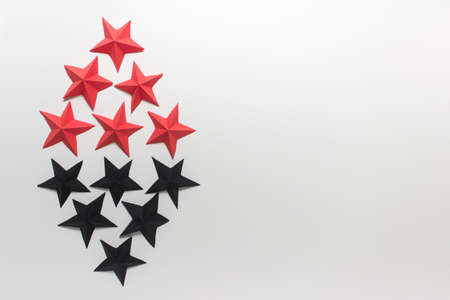 Paper origami folded stars red and black arranged in diamond rhombus shape on white background. Decorative photo mockup with copy blank space.の写真素材