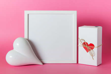 Pink white mockup composition with white blank frame, heart, wrapped present for Mothers, Fathers, Valentine's day.の写真素材