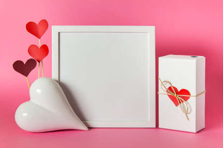 Cheerful mockup composition for Mothers, Fathers, Valentine's day with white blank frame, heart, wrapped present and red hearts.の写真素材