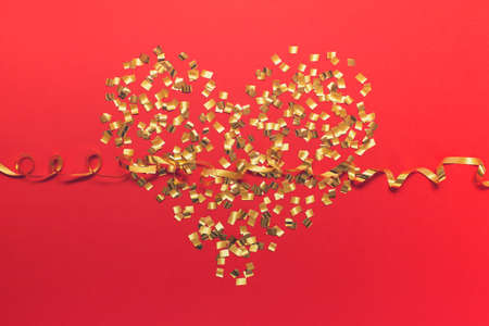 Greeting card for Valentine, Mother, Father day with golden glitter and golden wavy ribbon on red backgound. の写真素材