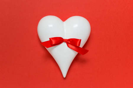 Valentine mother father day greeting card with white porcelain heart and red satin bow on red background.の写真素材