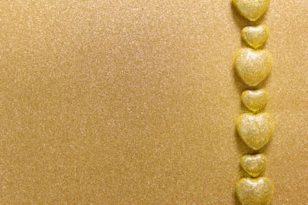 Simple minimalistic golden valentine day background with a row of  golden hearts and empty blank space for text.の写真素材