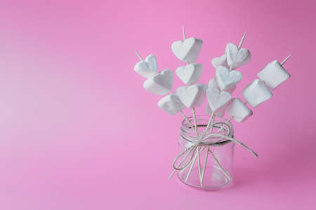 Sweet decoration with heart shaped marshmallows on wooden sticks on pink background. Photo with copy blank space.の写真素材