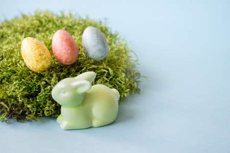 Festive greeting card with Easter decorative elements eggs, rabbit bunny and wild forest green moss...