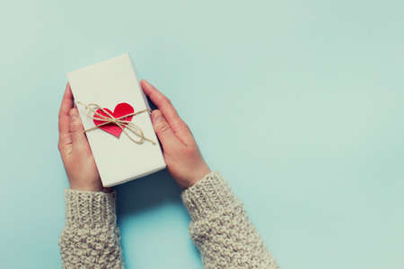 Female hands holding a present with red heart and a bow of packthread. Thank you for greeting card with copy blank space.の写真素材