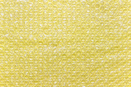 Yellow  air filled transparent packaging foil placed on yellow backgound.