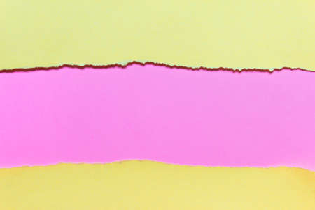 Yellow and pink paper layers with ripped uneven edges. Photo with copy blank space.