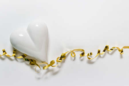 Greeting invitation gratitude love affection expression card with white porcelain hearts and twisted golden ribbon on white background.の写真素材