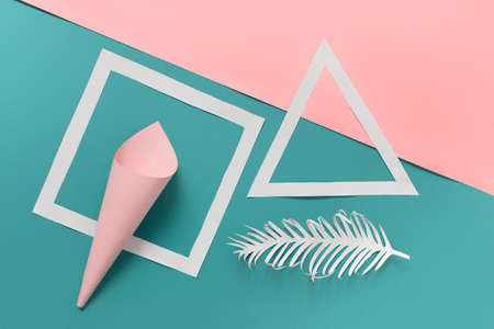 Minimalistic composition with paper shapes - cone, square, triangle and white paper origami feather on pink blue background.の写真素材