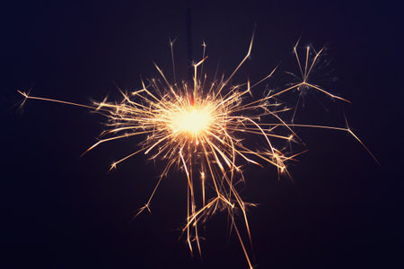 Close up of one burning pyrotechnic sparkler on dark background. Photo with magenta tint.の写真素材