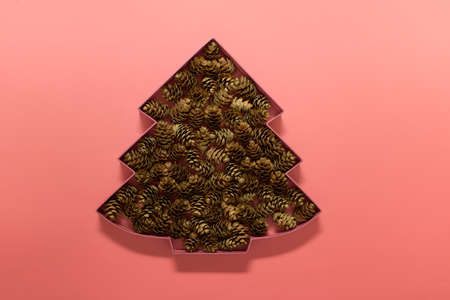 Greeting card with Christmas tree outline filled with real pine cones on pink background.の写真素材