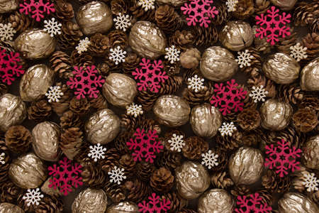 Festive Christmas background with many objects pinecones, golden walnuts, red and white snowflakes.