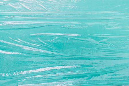 Mockup template background with folded uneven celofan food film foil on green paper background.